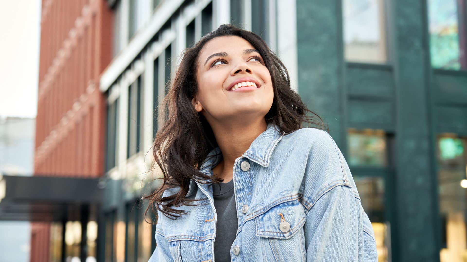 Gen Z woman smiling and walking outside.