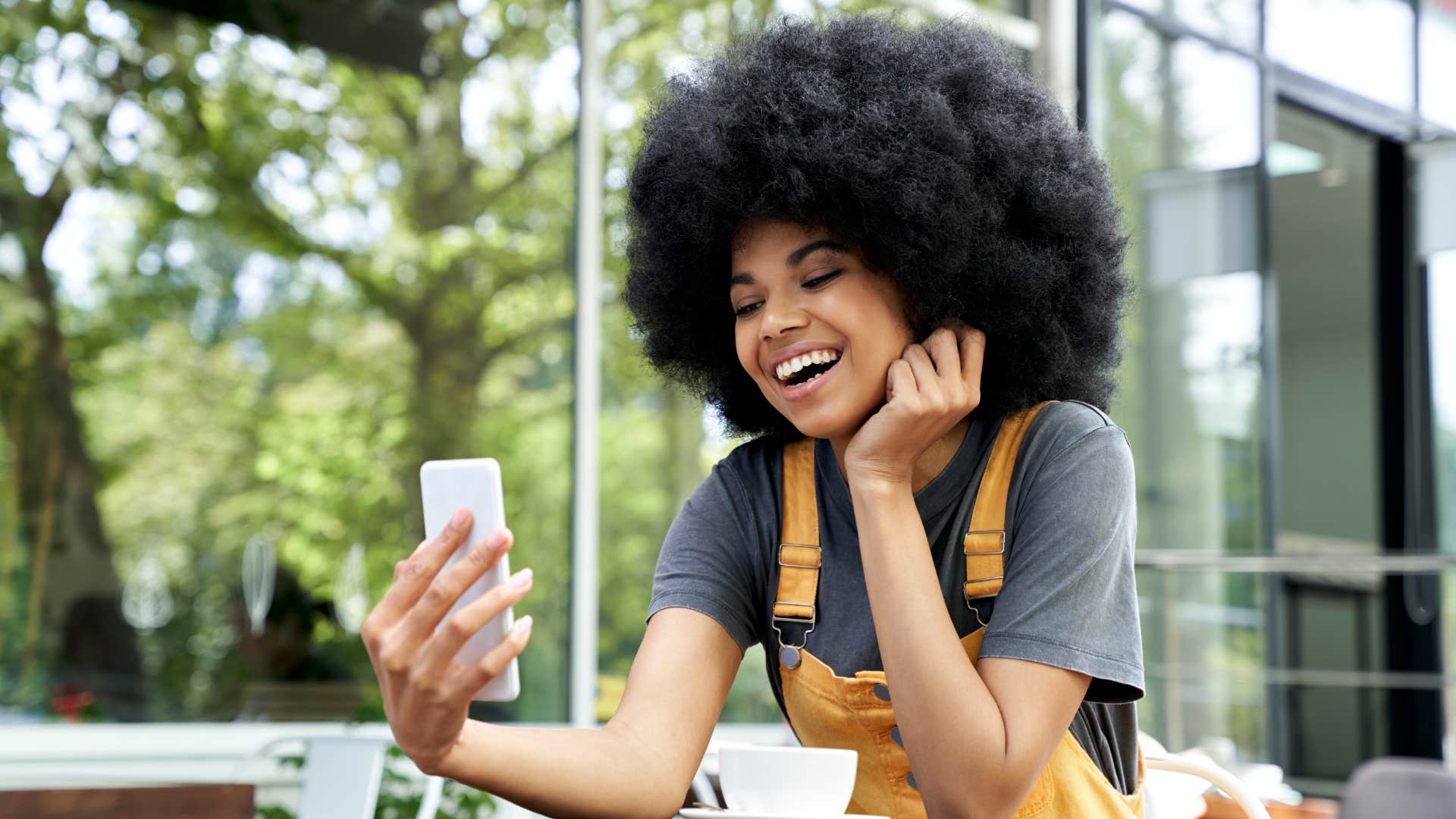 Gen Z woman smiling at her phone.