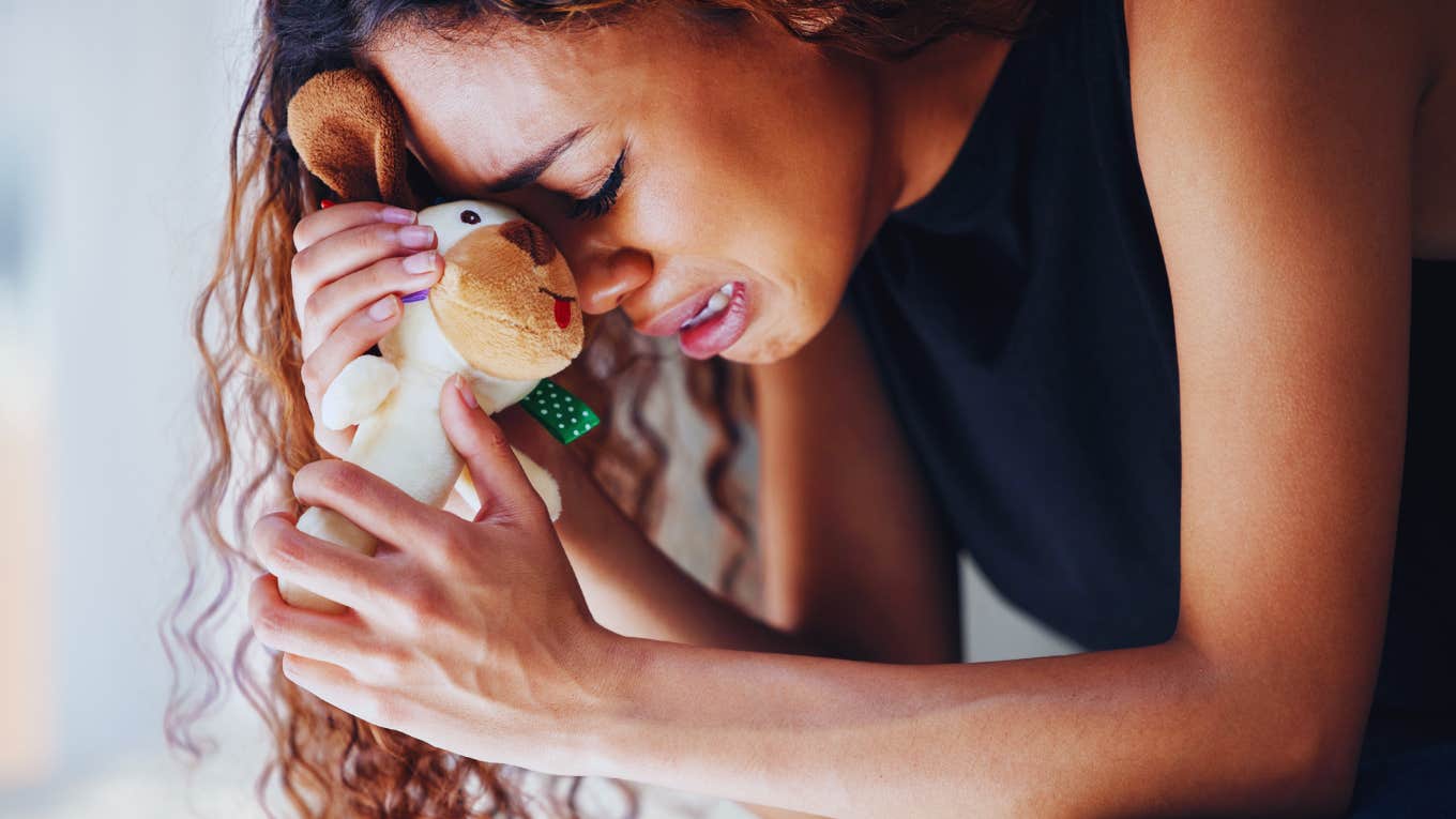 The Profound Grief Of Having No Proof That Your Baby Existed Grieving woman, holding on to babies toy.