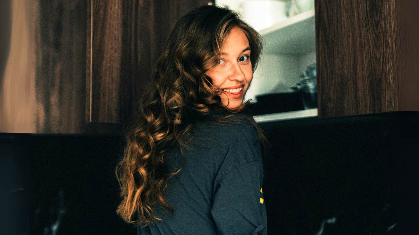 Daily Habits Of People With A High Confidence-Intelligence Ratio, According To Psychology Smart, confident woman standing casually in kitchen.