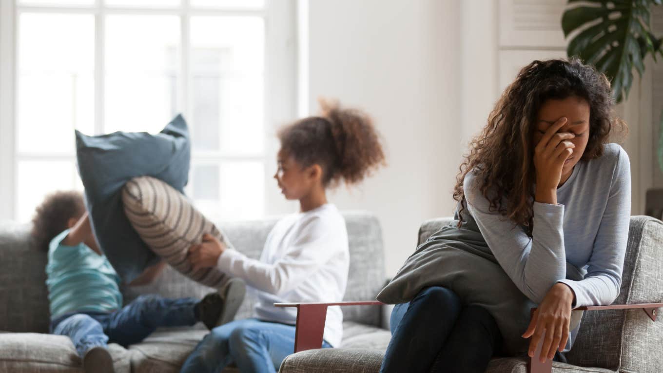 Mom Fed Up With Family Wanting Her To Bring The Kids To Them For Visits overwhelmed mom sitting while kids play behind her
