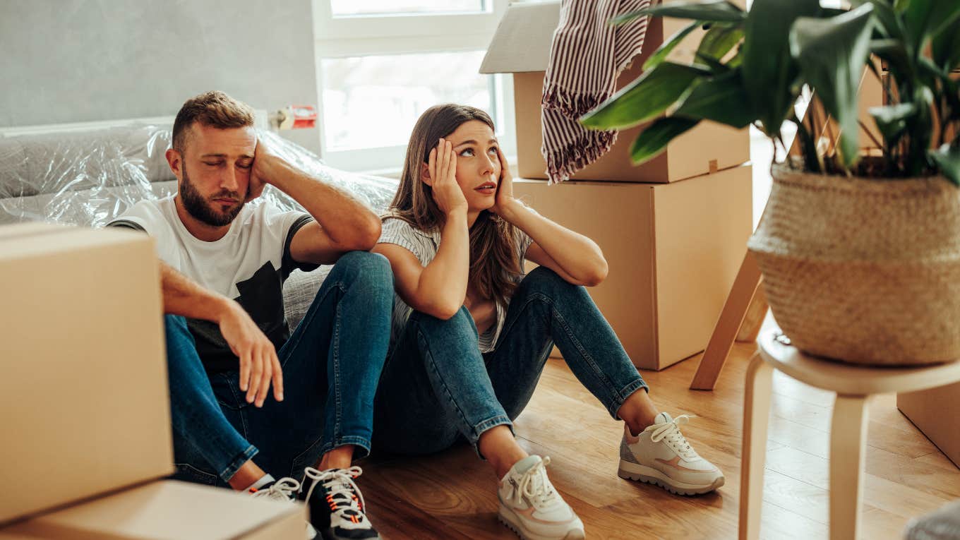 Signs It's Not Your Marriage That's The Problem -- It's Your House Upset couple surrounded by clutter in their home.