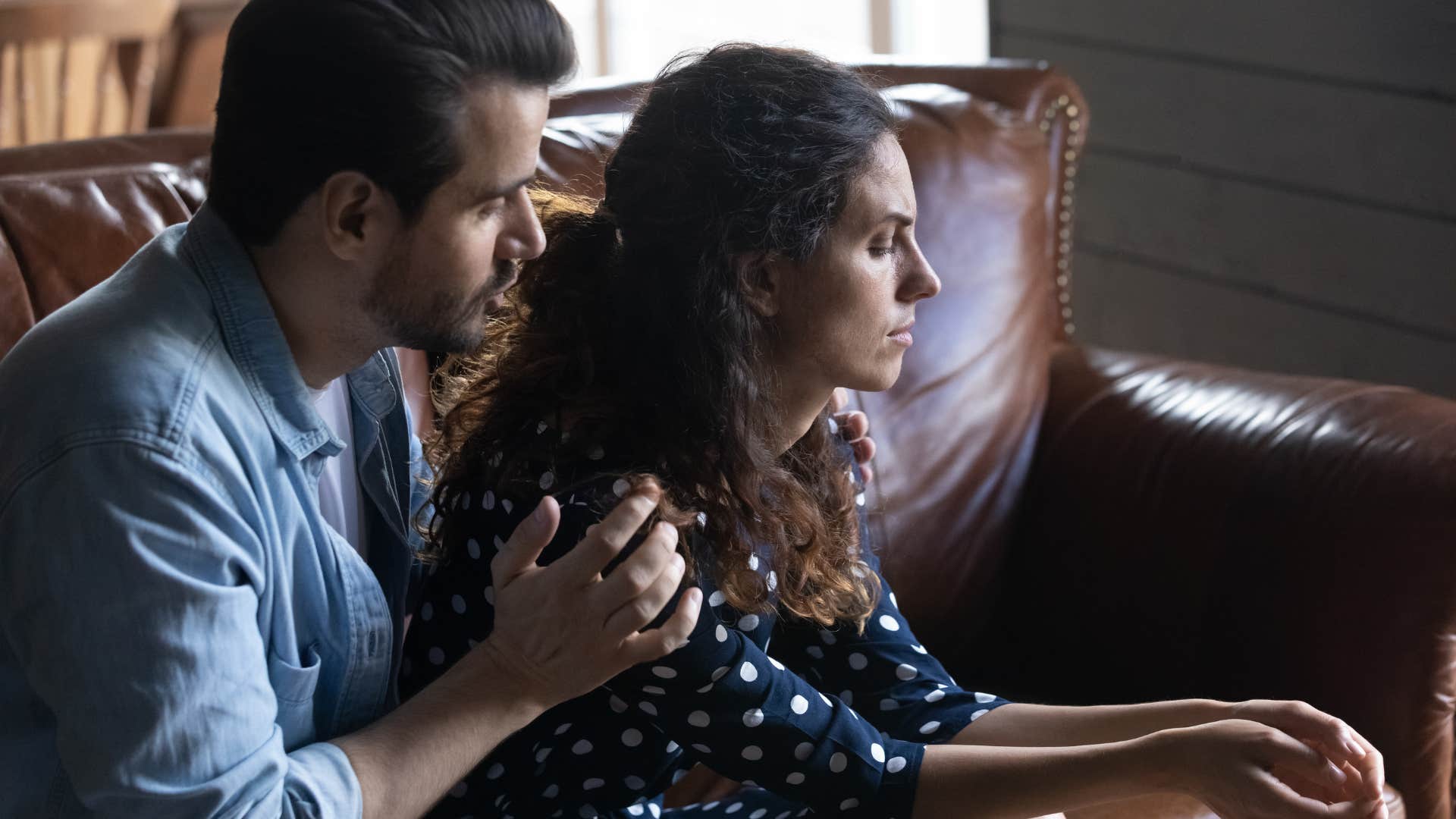 Man comforting his upset wife in their home.