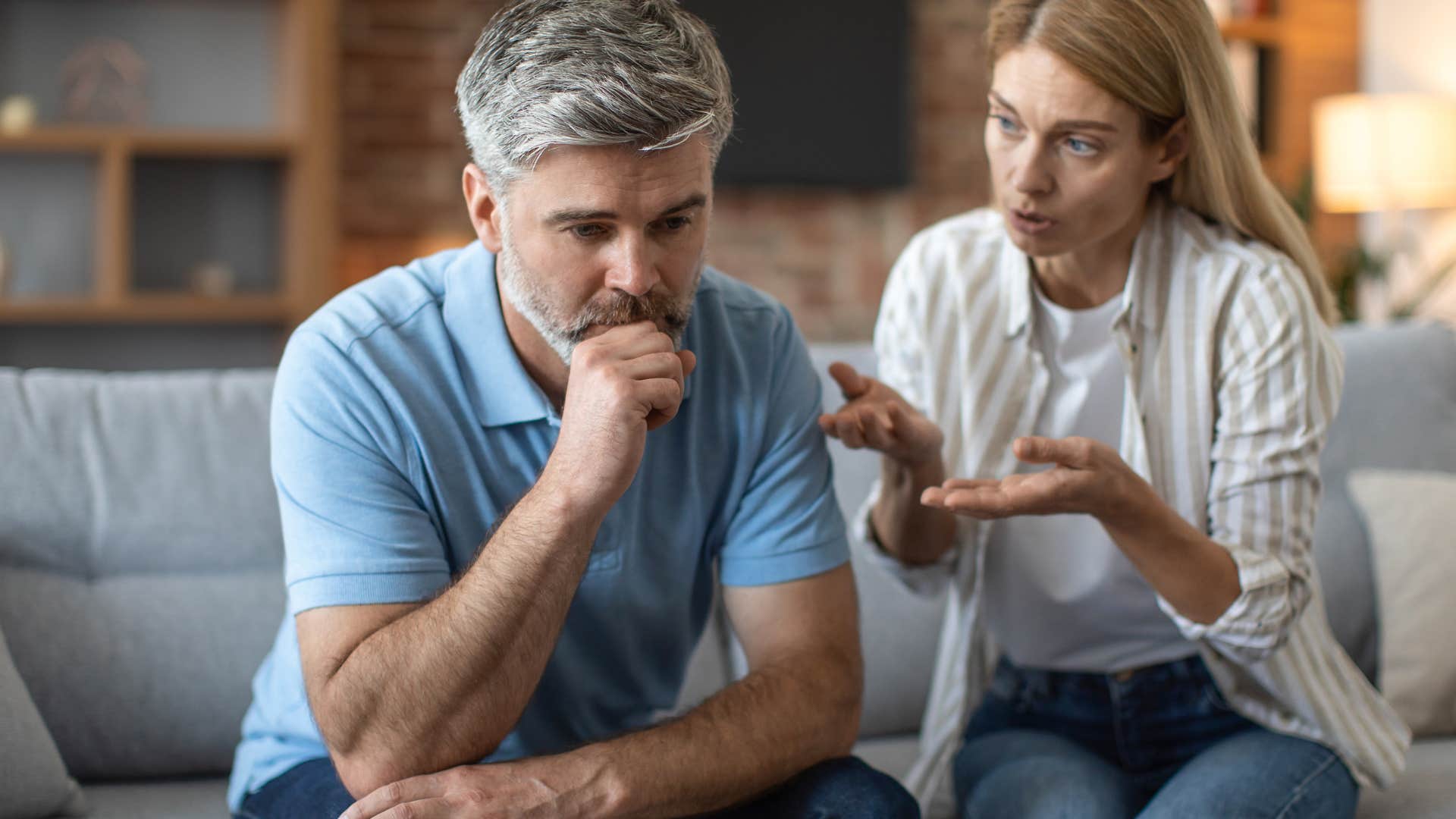 Older couple looking upset arguing on the couch.