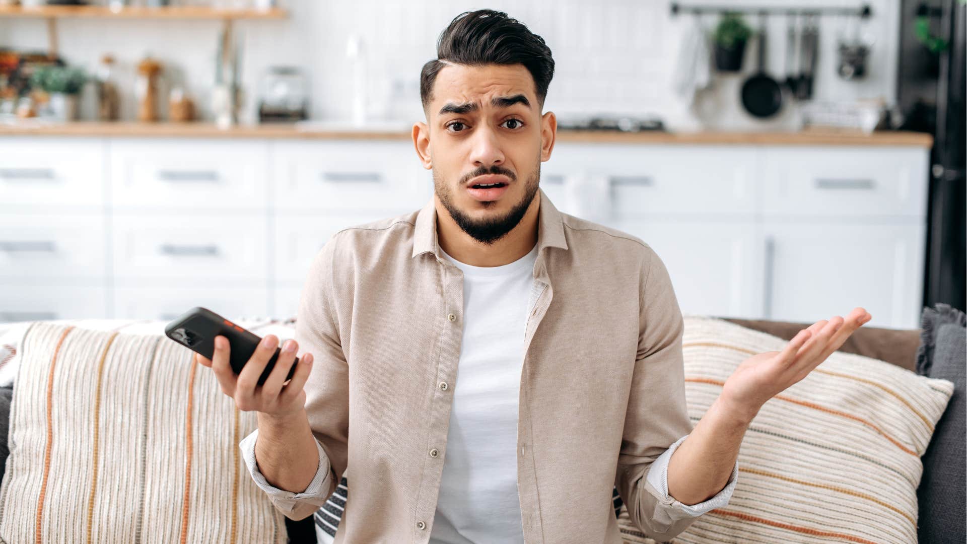 Man looking confused holding his cell phone.