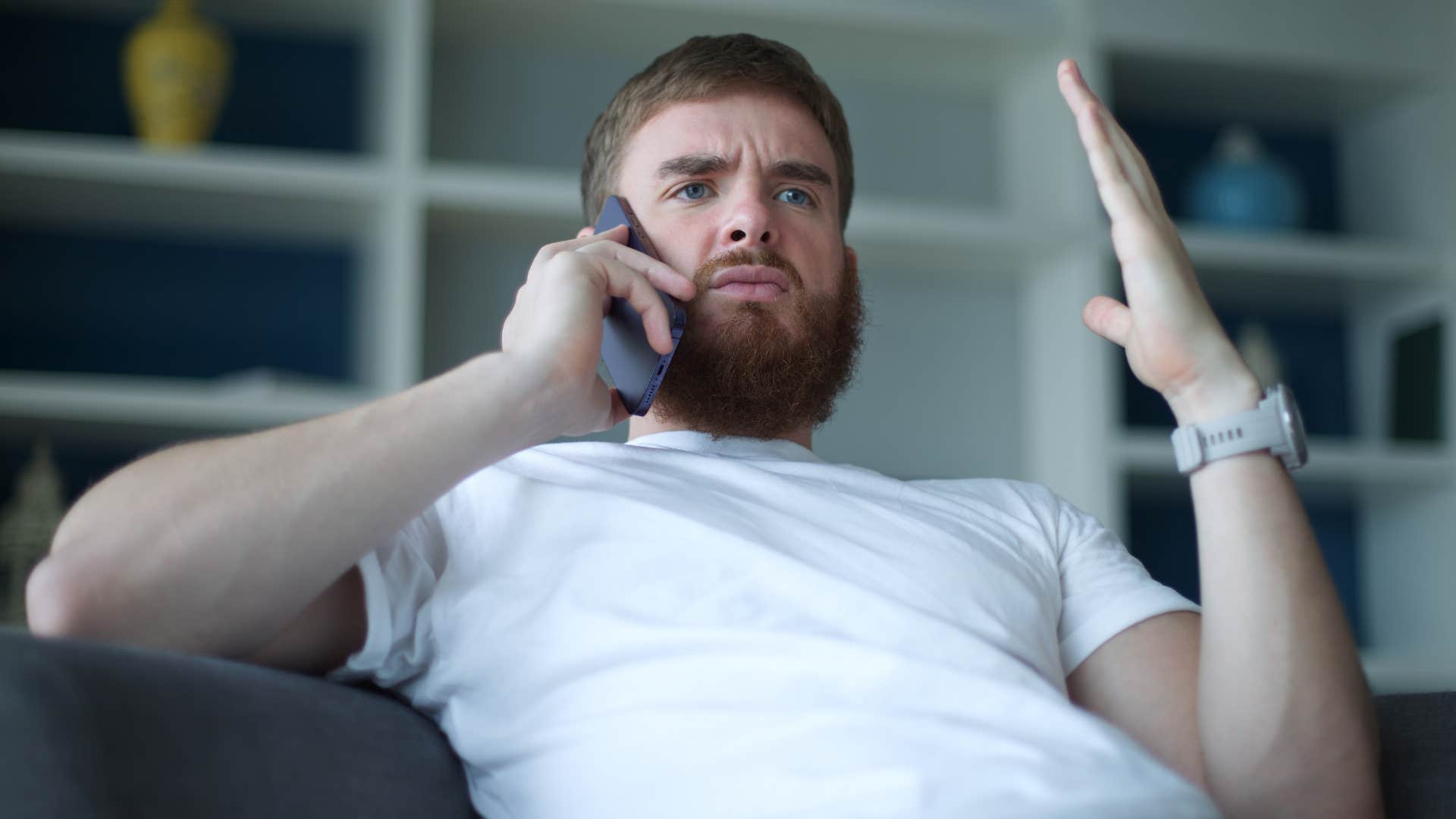 Adult man looking annoyed talking on the phone.