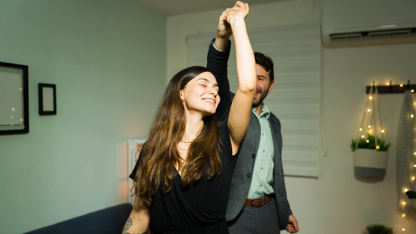 2 Signs You're In A Couple Bubble — And It's Saving Your Marriage Beautiful young woman enjoying a slow dance with her husband in their living room home