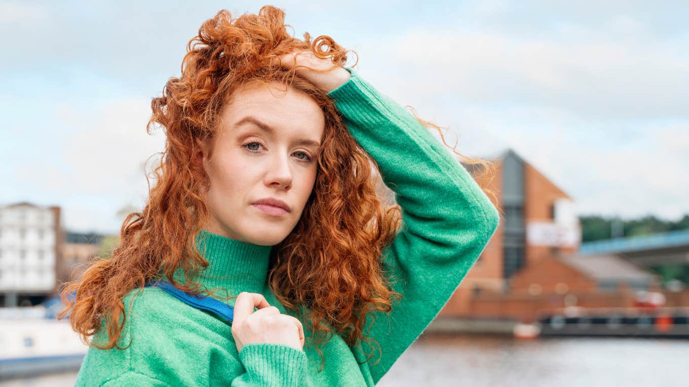 Signs Someone In Your Life Is Experiencing Deep Emotional Pain, According To Psychology redheaded woman with curly hair posing outside