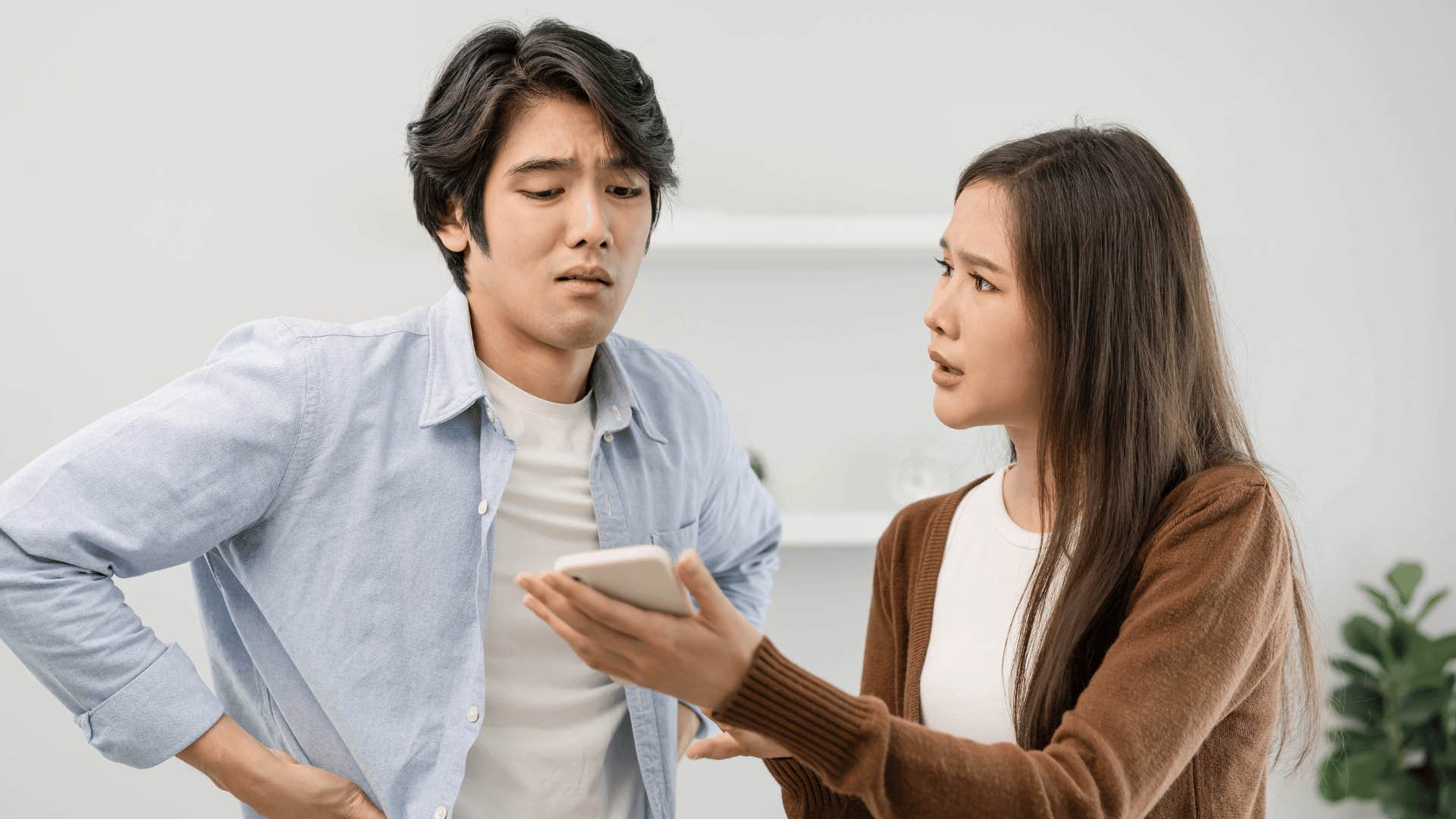 She shows him a mobile device, he looks defensive