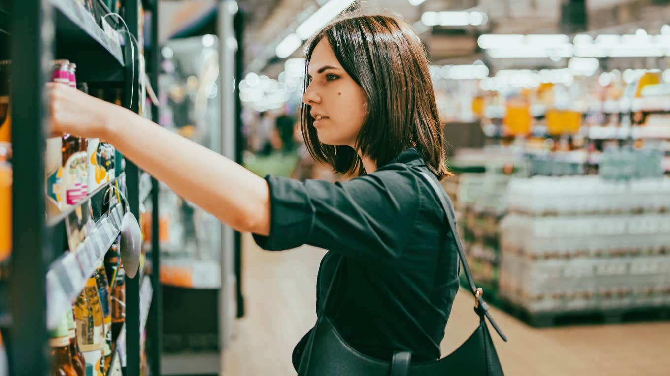 Young woman choosing drinks to buy in a supermarket