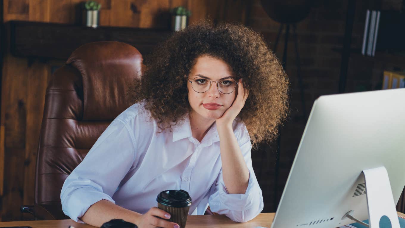 Worker Shocked When Bosses Warn It's Policy To Be Fired For Discussing Pay Employee sitting at desk with a cup of coffee