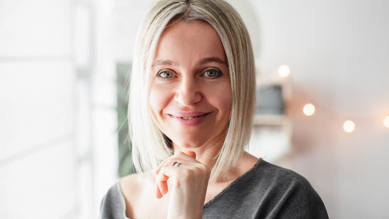 Common Behaviors That Make Even Smart People Look Uneducated Older blonde woman smiling while looking at the camera.
