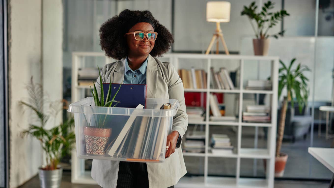 Laid Off White Collar Worker Admits The Job Market Is Dehumanizing Young smiling african businesswoman entering in office and carrying box with her working supplies while going back to work