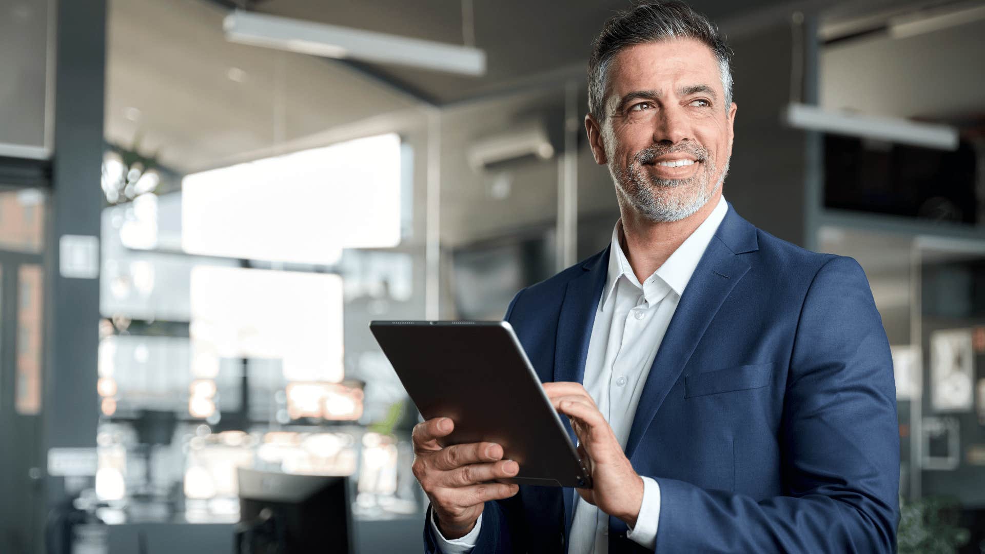 man staring off into space while holding tablet 