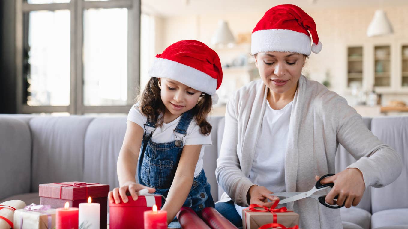 Mom Accused Of Being Cruel For Thrifting All Of Her Kids Christmas Presents Young mother and little girl daughter using paper for wrapping Christmas presents