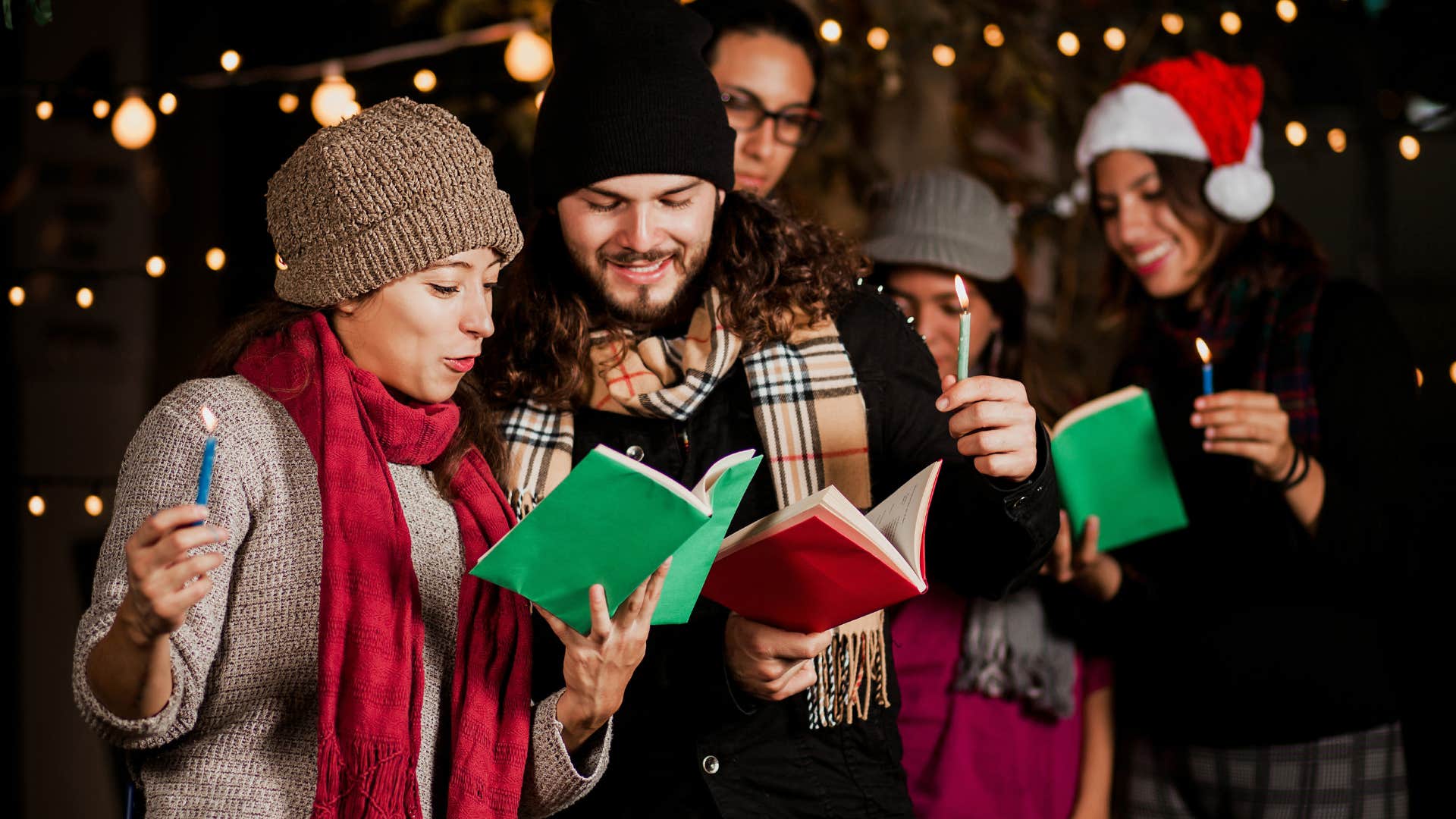 Holiday carolers smiling and singing outside.