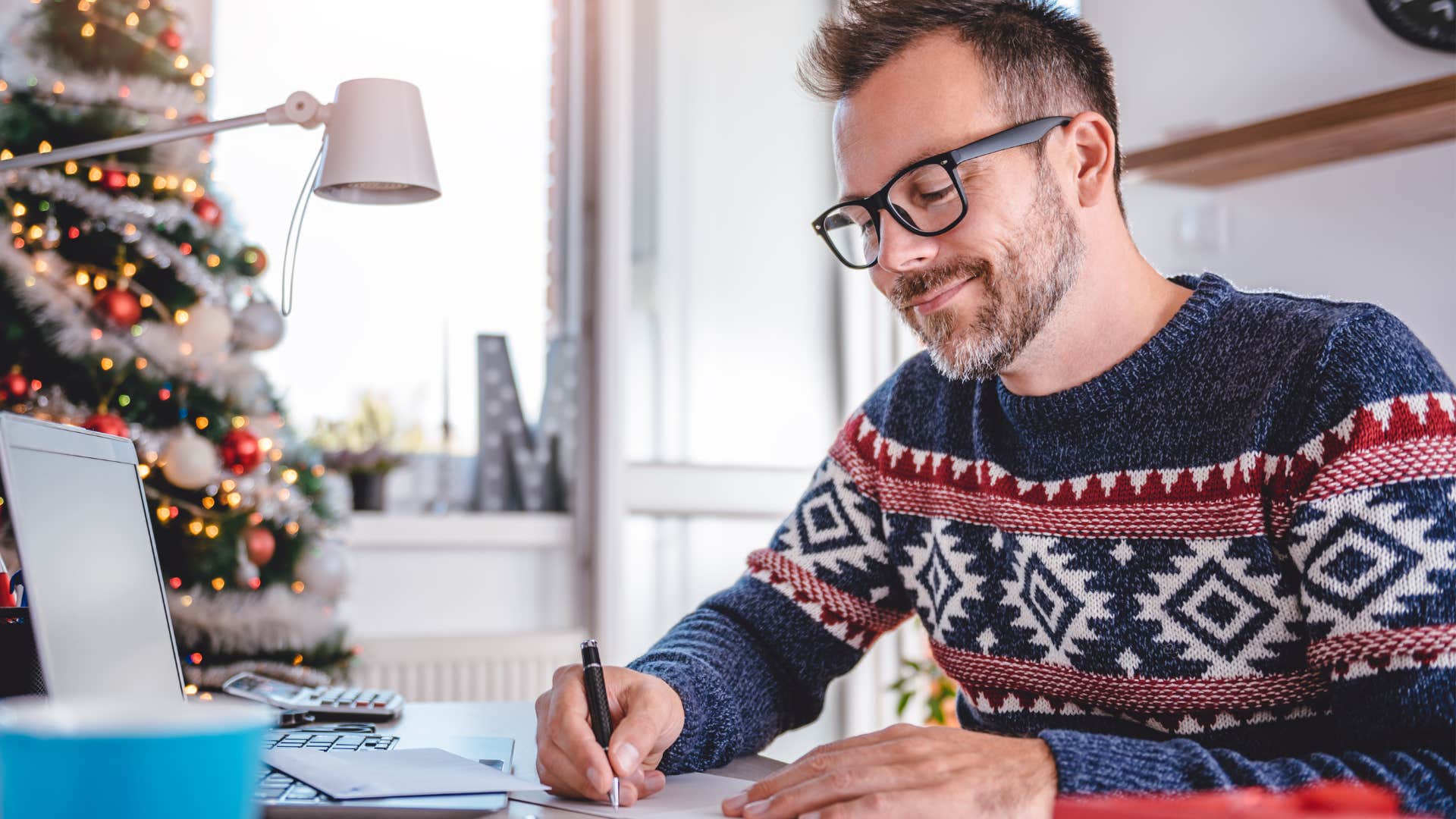 Man smiling and writing in a card.