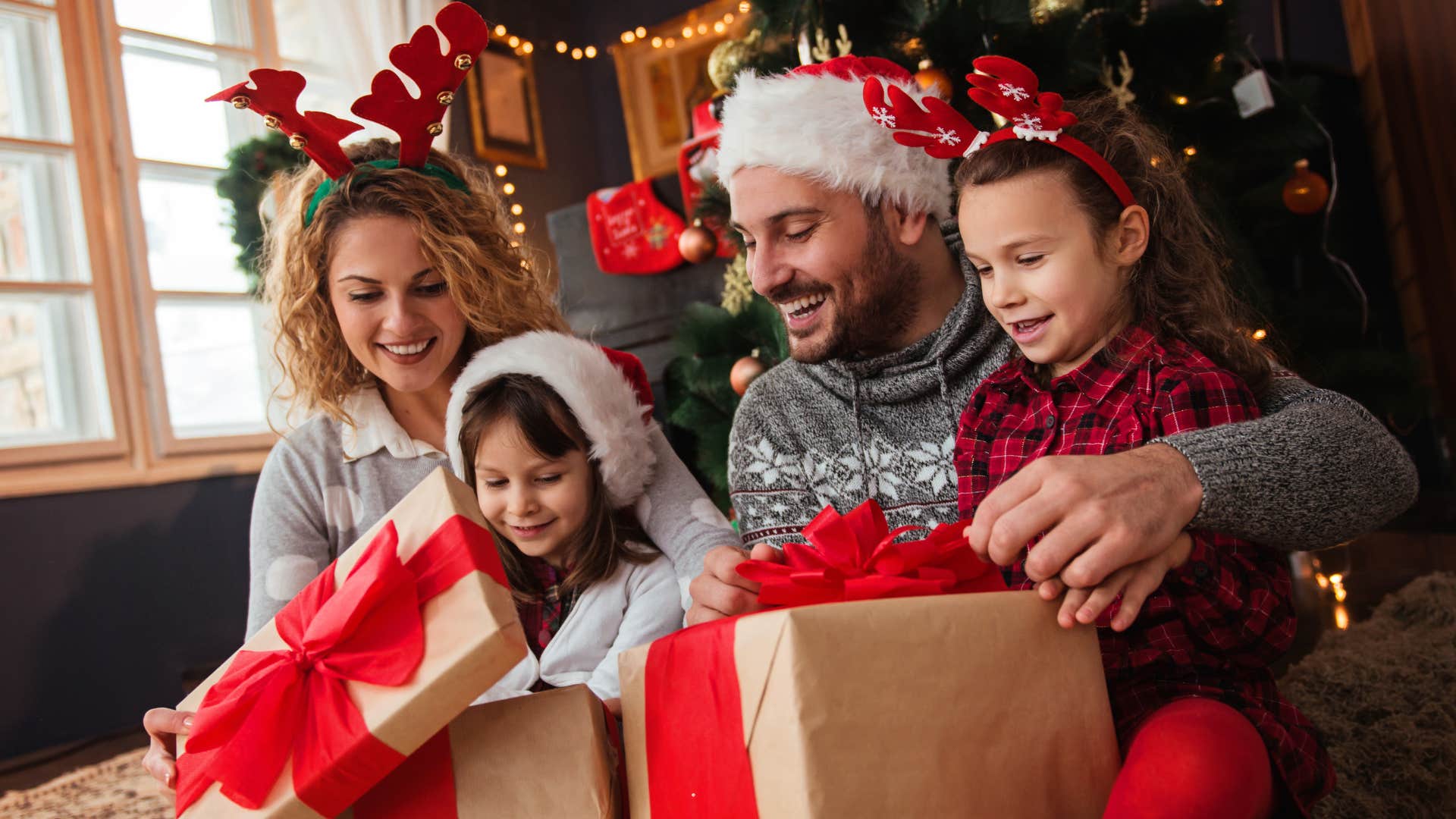 Family smiling and opening presents together under the tree. 