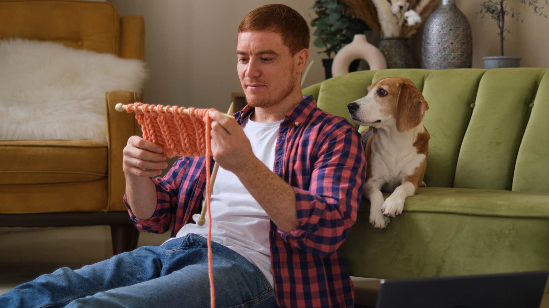 Man knitting on his living room floor. 