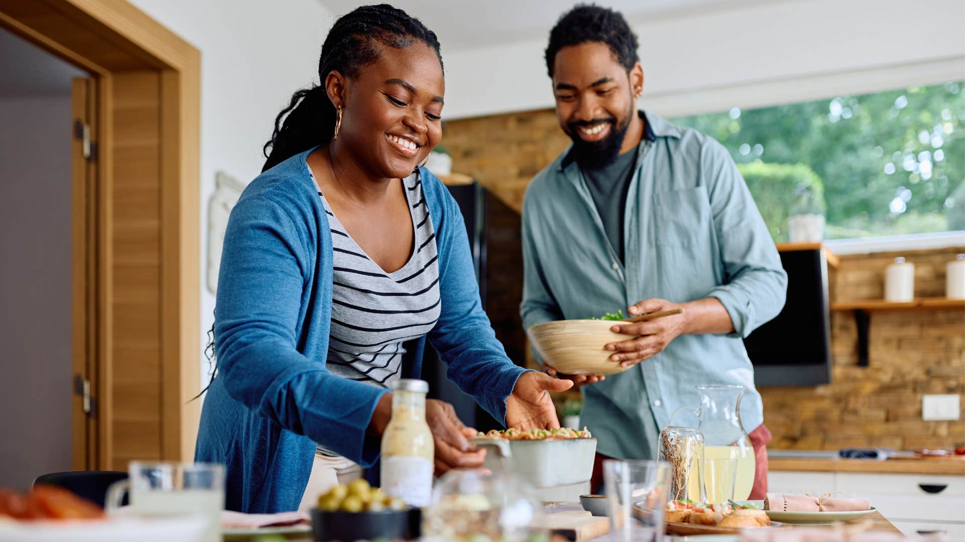 Couple smiling and setting the table in their home.