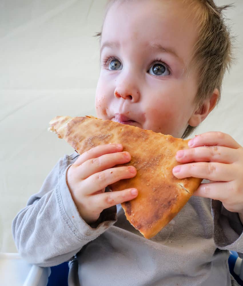 toddler eating slice of pizza