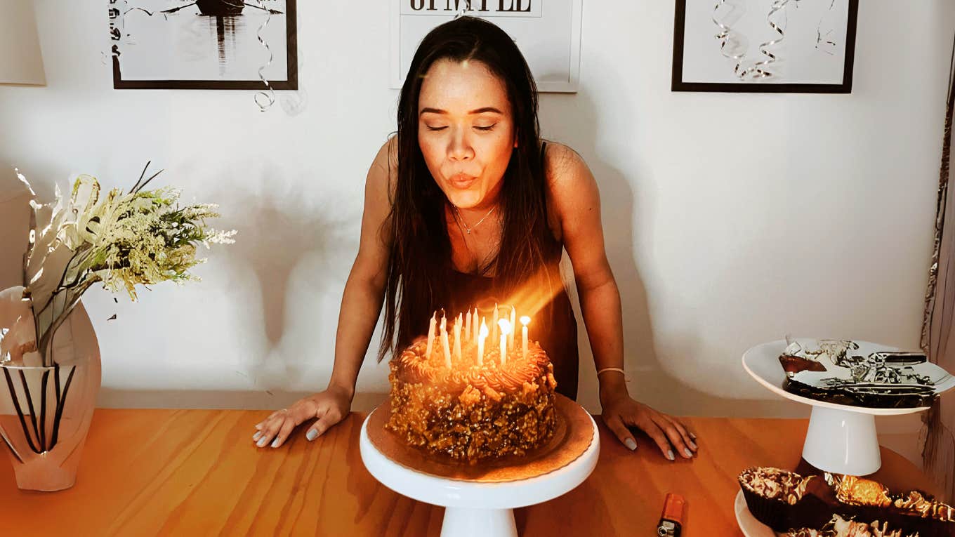 Traditions From Our Childhood Most People Don't Realize Are Pagan Woman blowing out birthday candle, celebrating childhood pagan tradition.