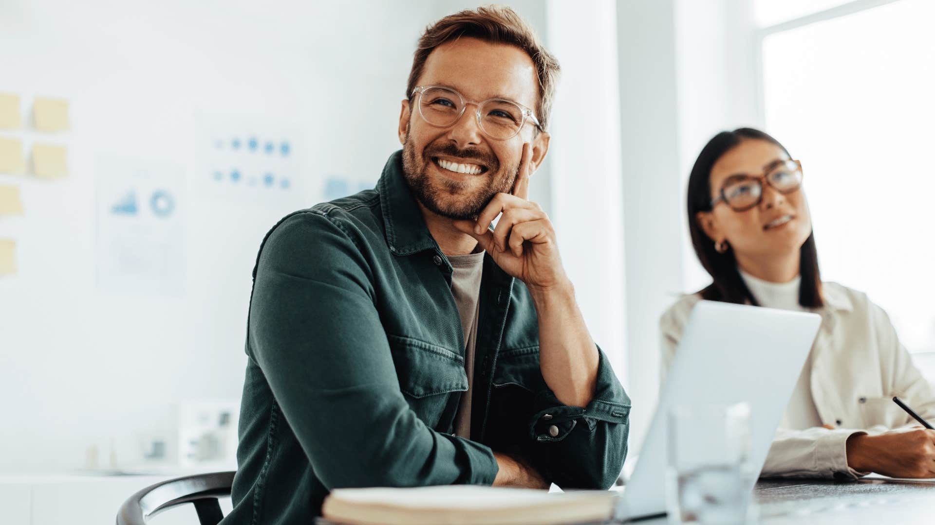 man listening to coworker while smiling 
