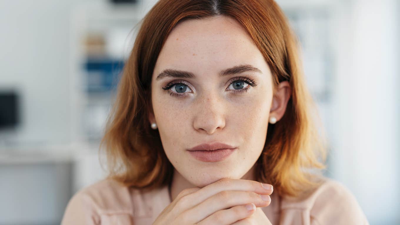 Subtle Traits Of A Truly Problematic Person, According To Psychology serious redheaded woman with hands on her chin