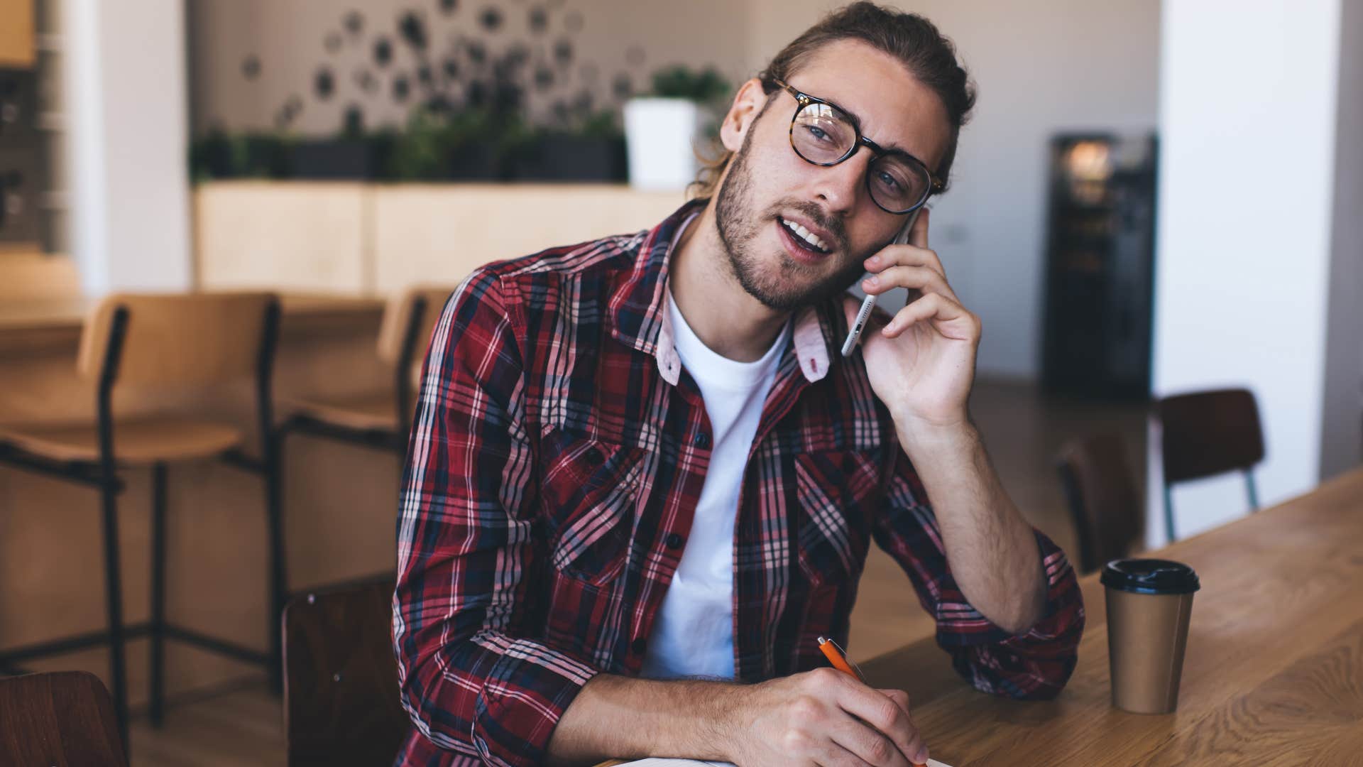 Man talking to someone on the phone in a coffee shop