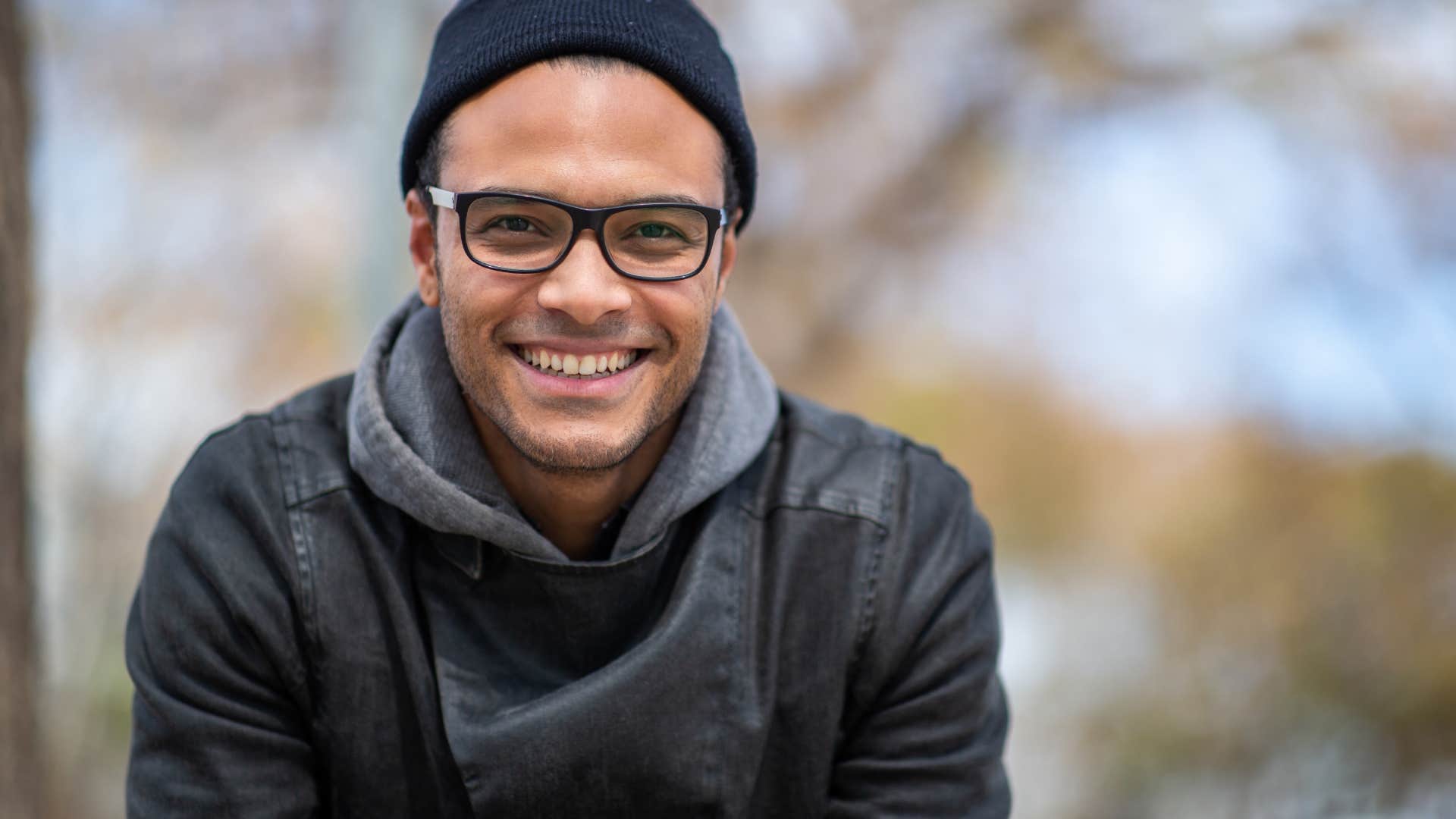 young man smiling sitting outside