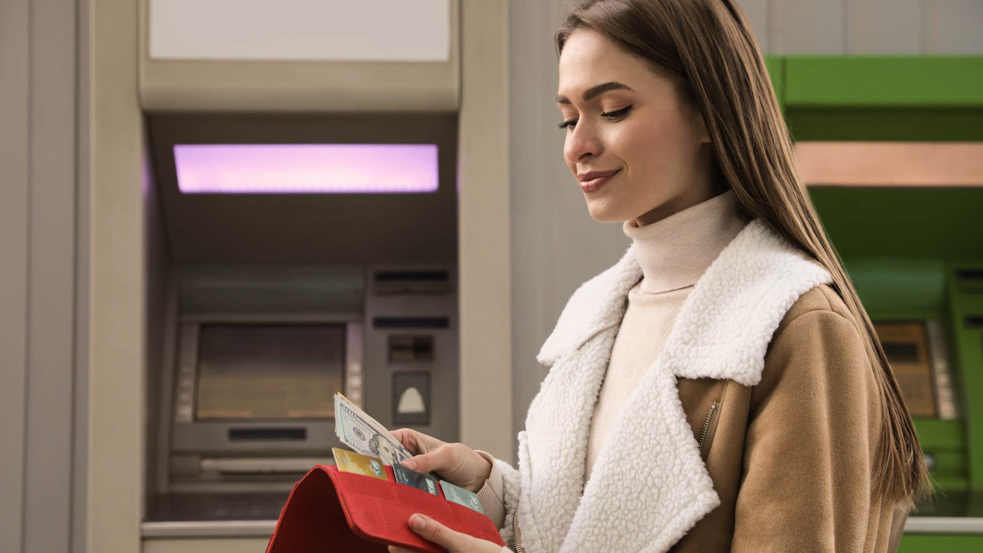 woman counting money in front of atm machine