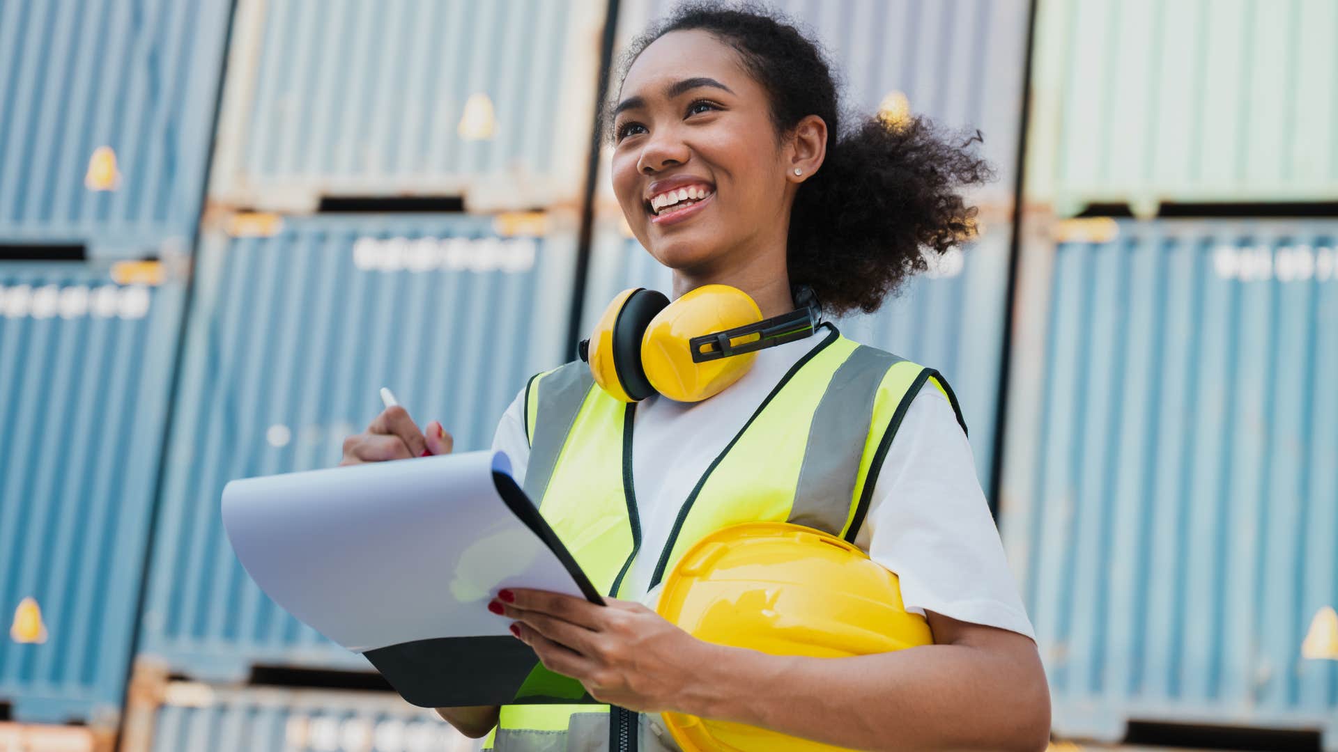 Woman smiling in a construction vest holding a clipboard