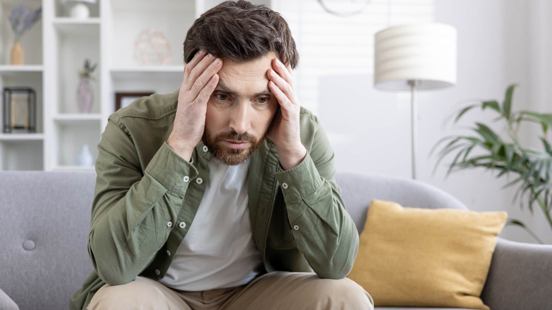 confused man holding his head in his hands
