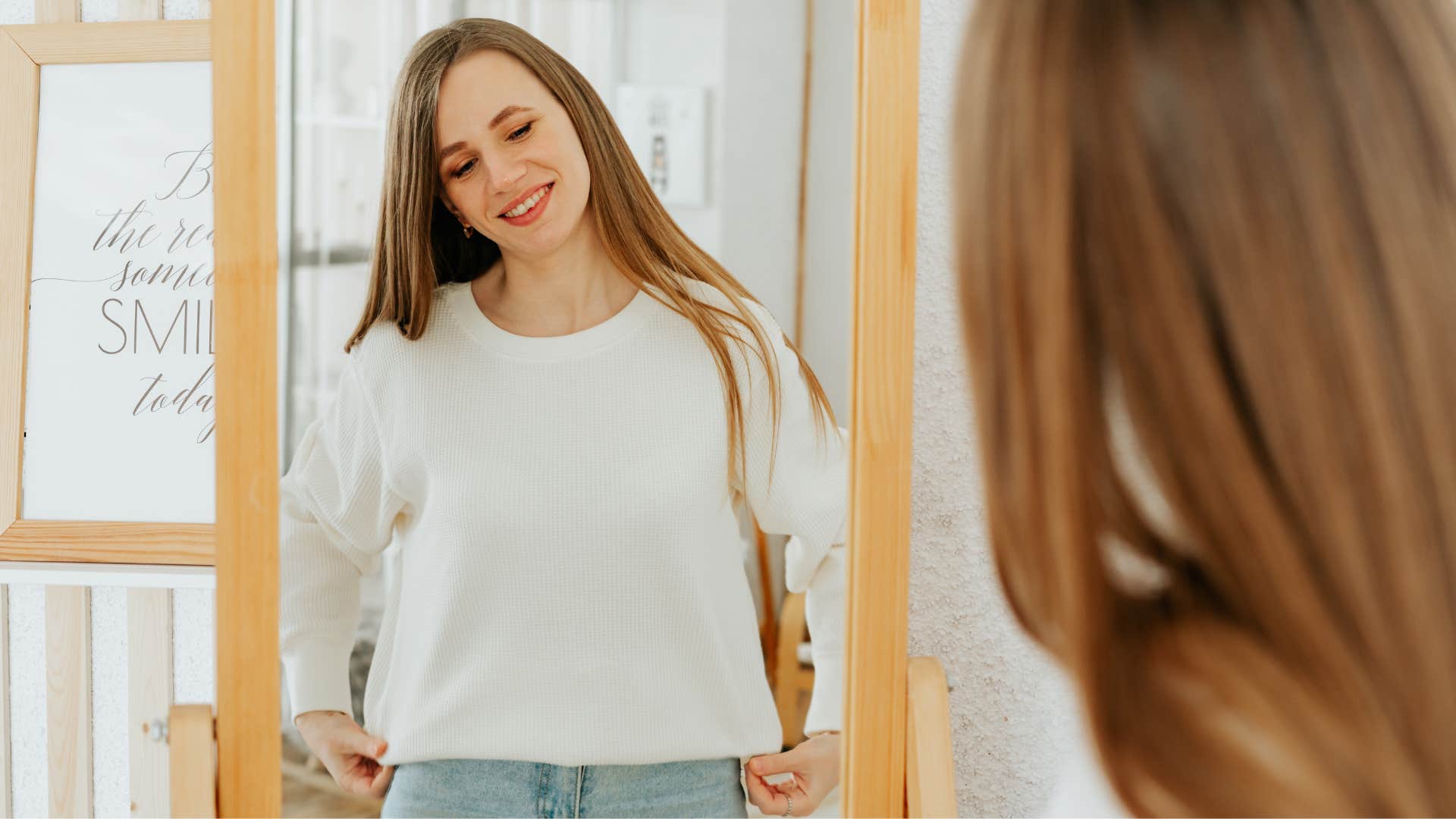 woman fixing clothes in the mirror