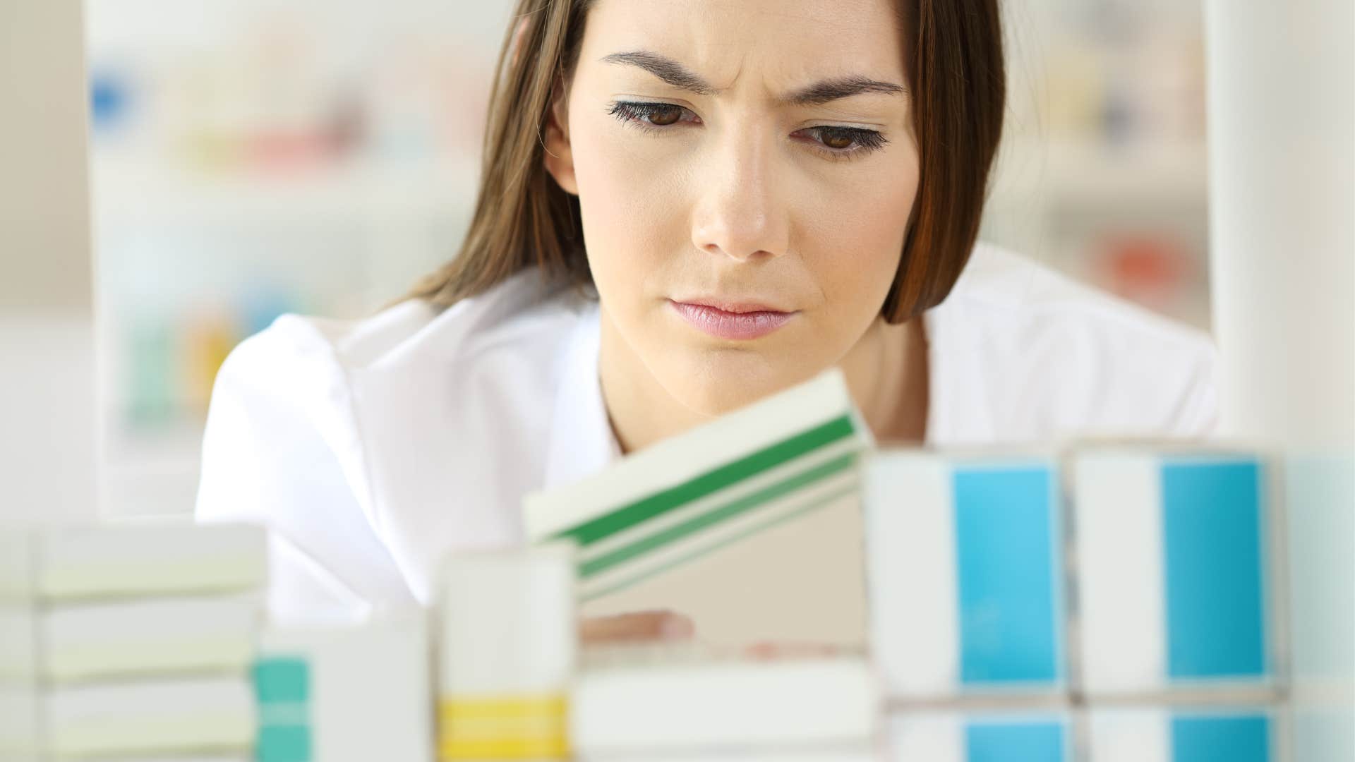 A woman looks at her expired medicine in the cabinet
