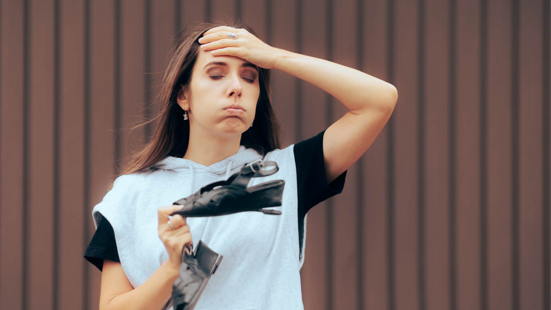 A woman holds her worn down shoes