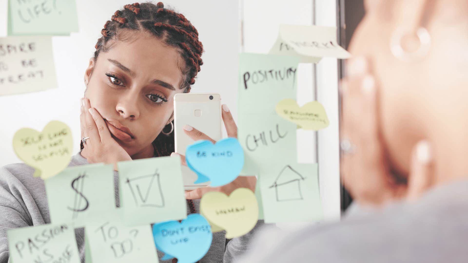 woman reading positive notes to herself in the mirror