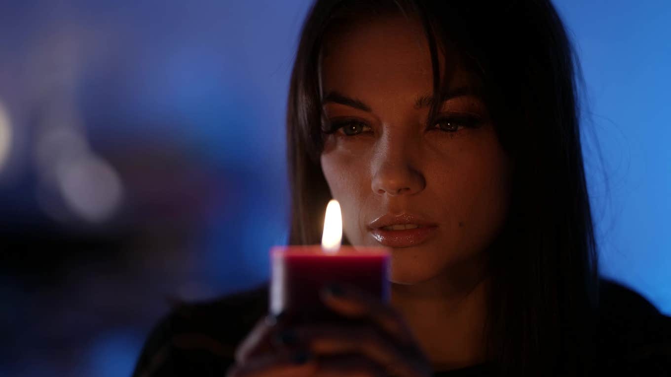 The Candle Theory Reveals Exactly How Someone Feels About Themselves A woman holding and looking into candle which reveals how someone feels about themselves