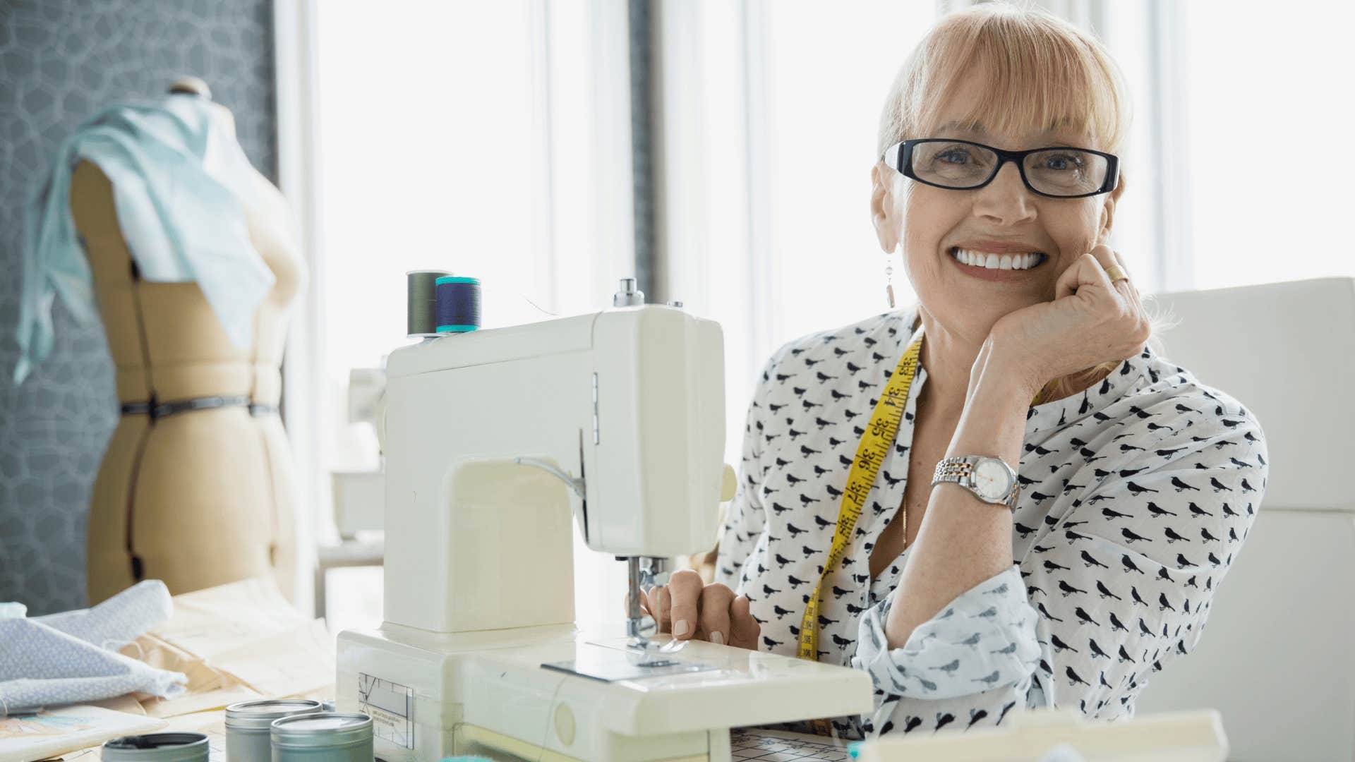 older woman smiling next to sewing machine