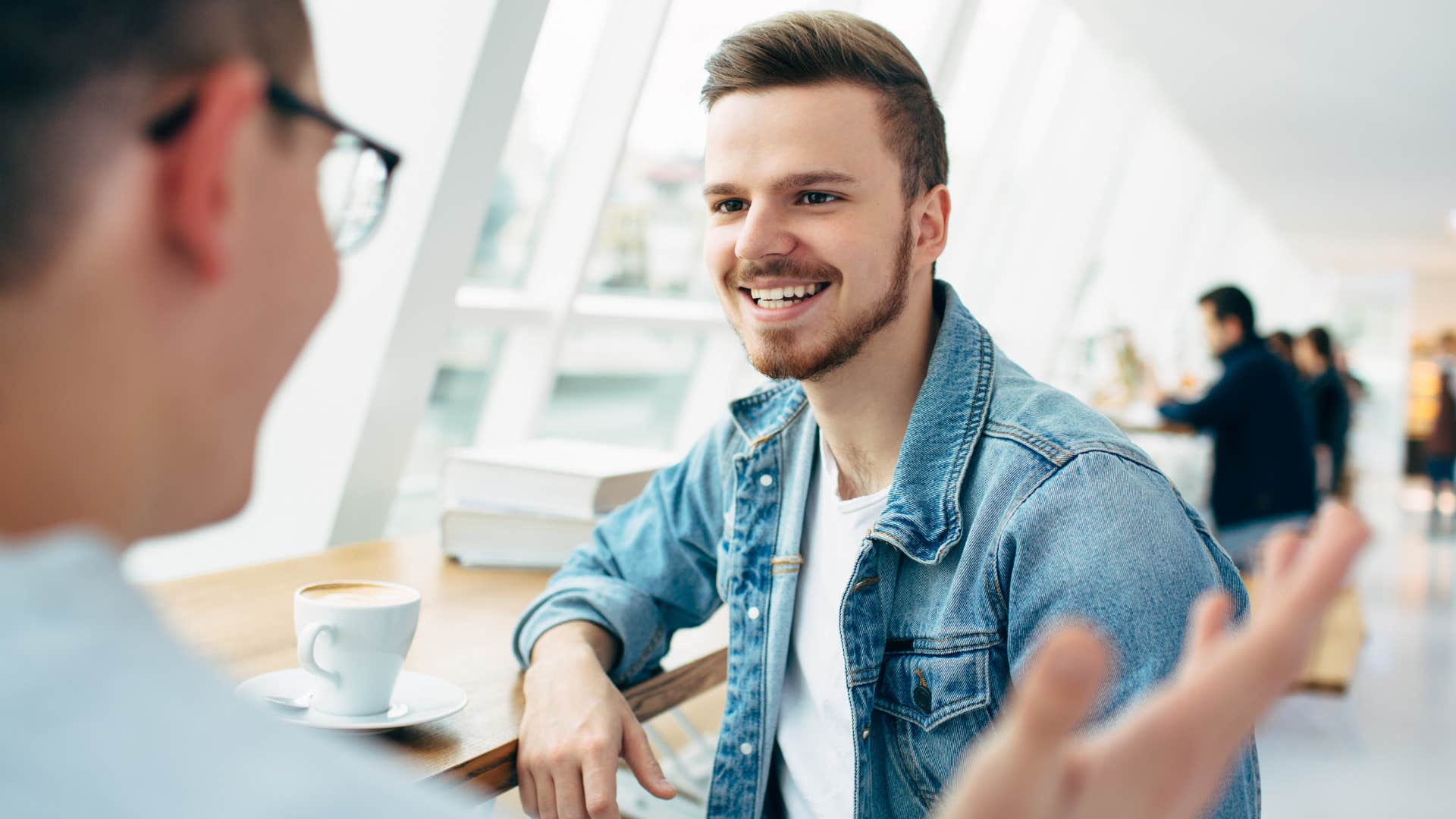 Man smiling and saying like you know to his friend in a coffee shop