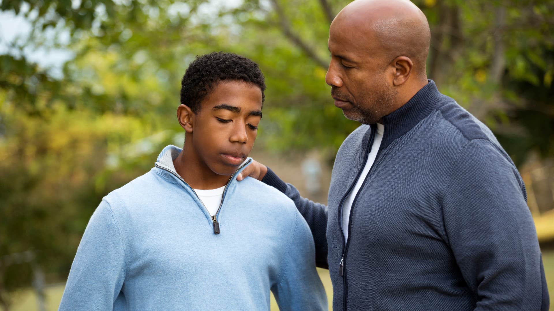 Man saying i'll own that and patting his upset teenage son's back outside