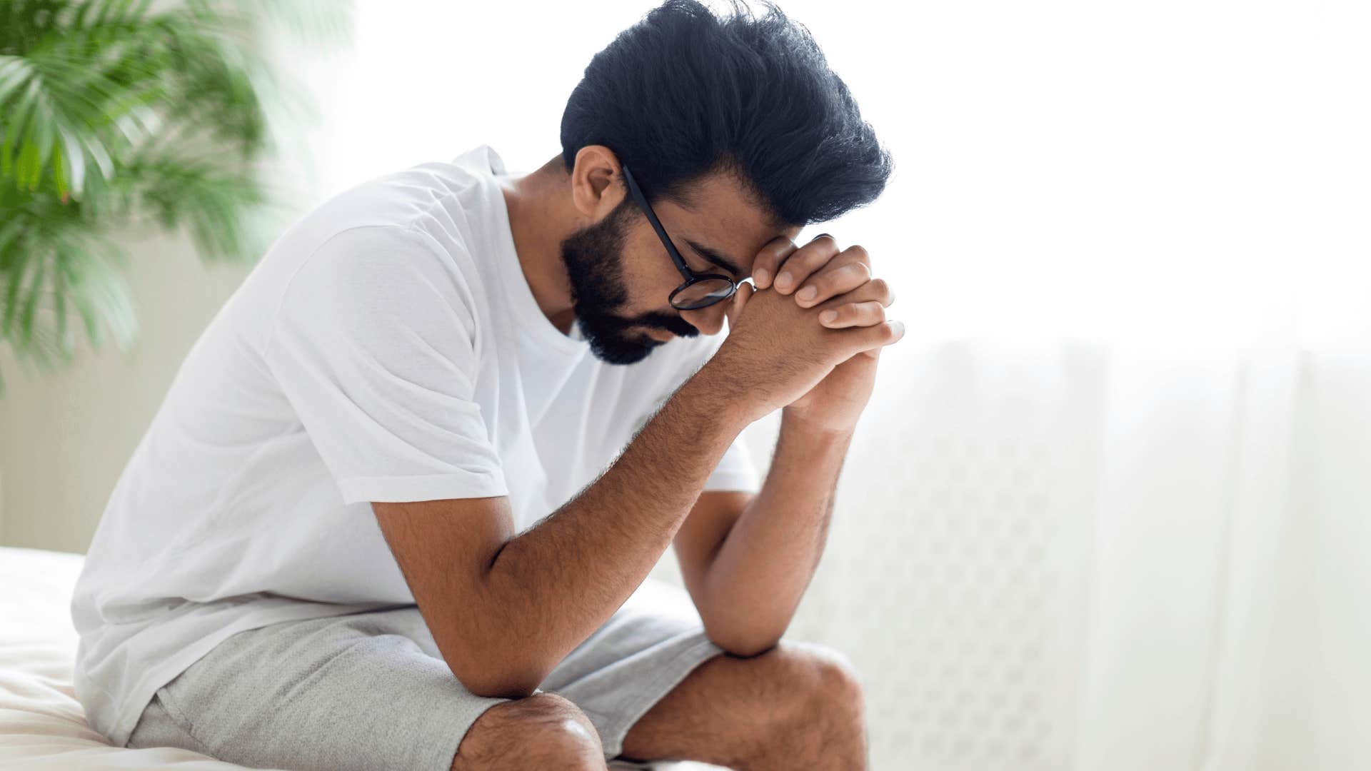 upset man sitting on bed thinking about regrets 