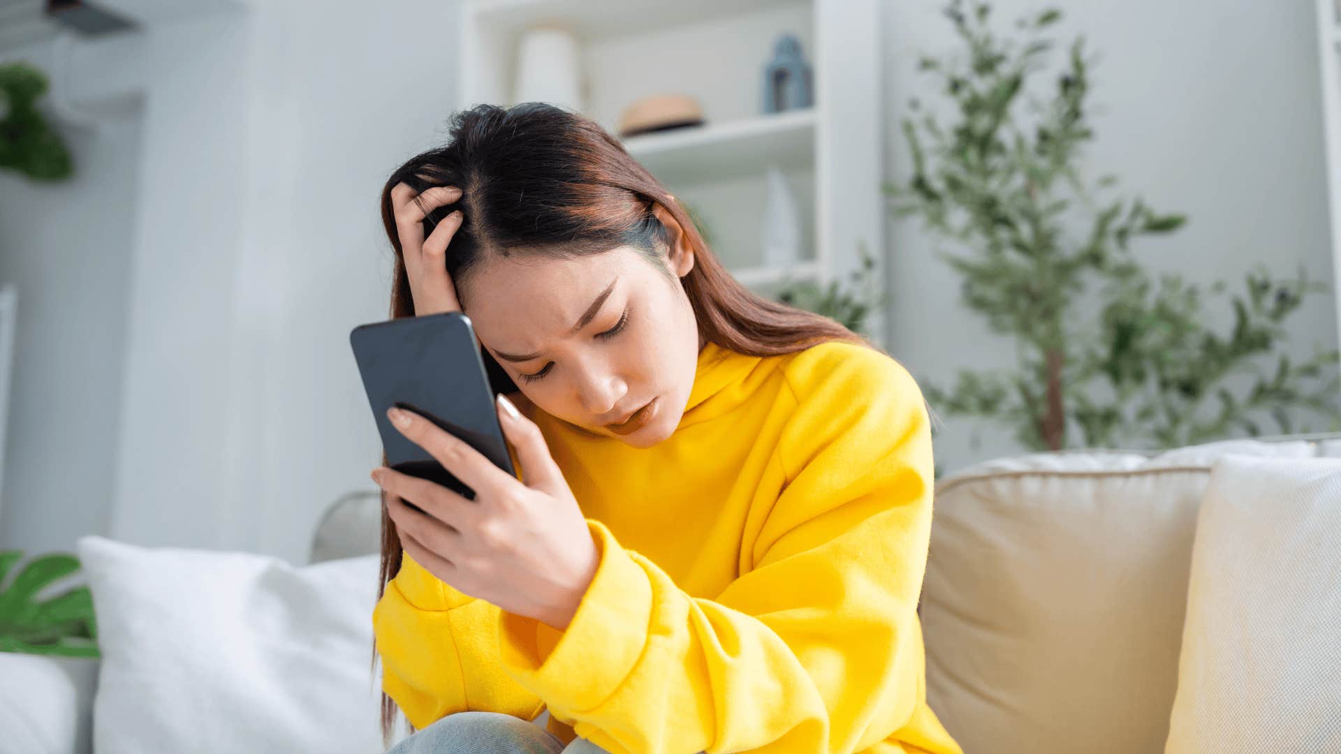 upset woman holding phone thinking about regrets