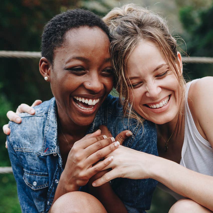 Two joyful women laugh and hug