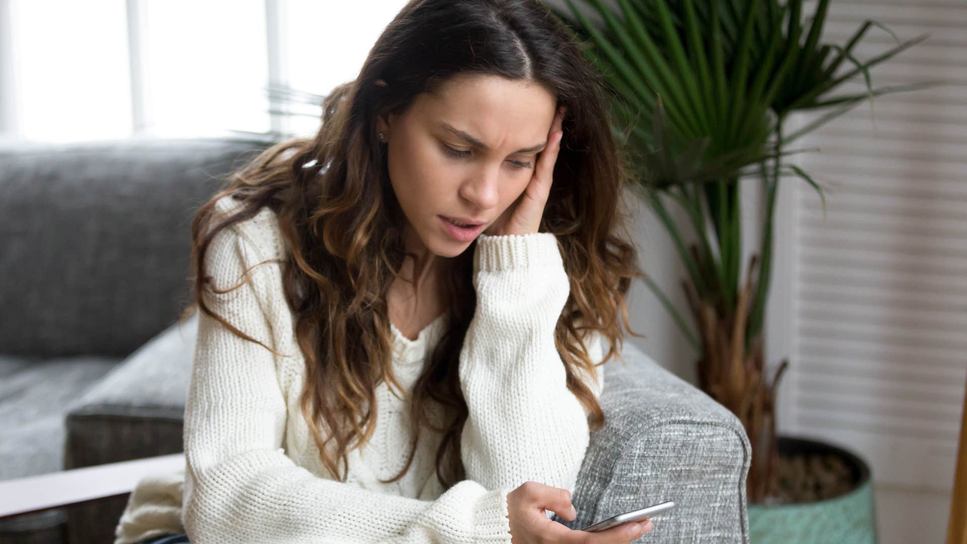 sad woman reading text messages on her phone