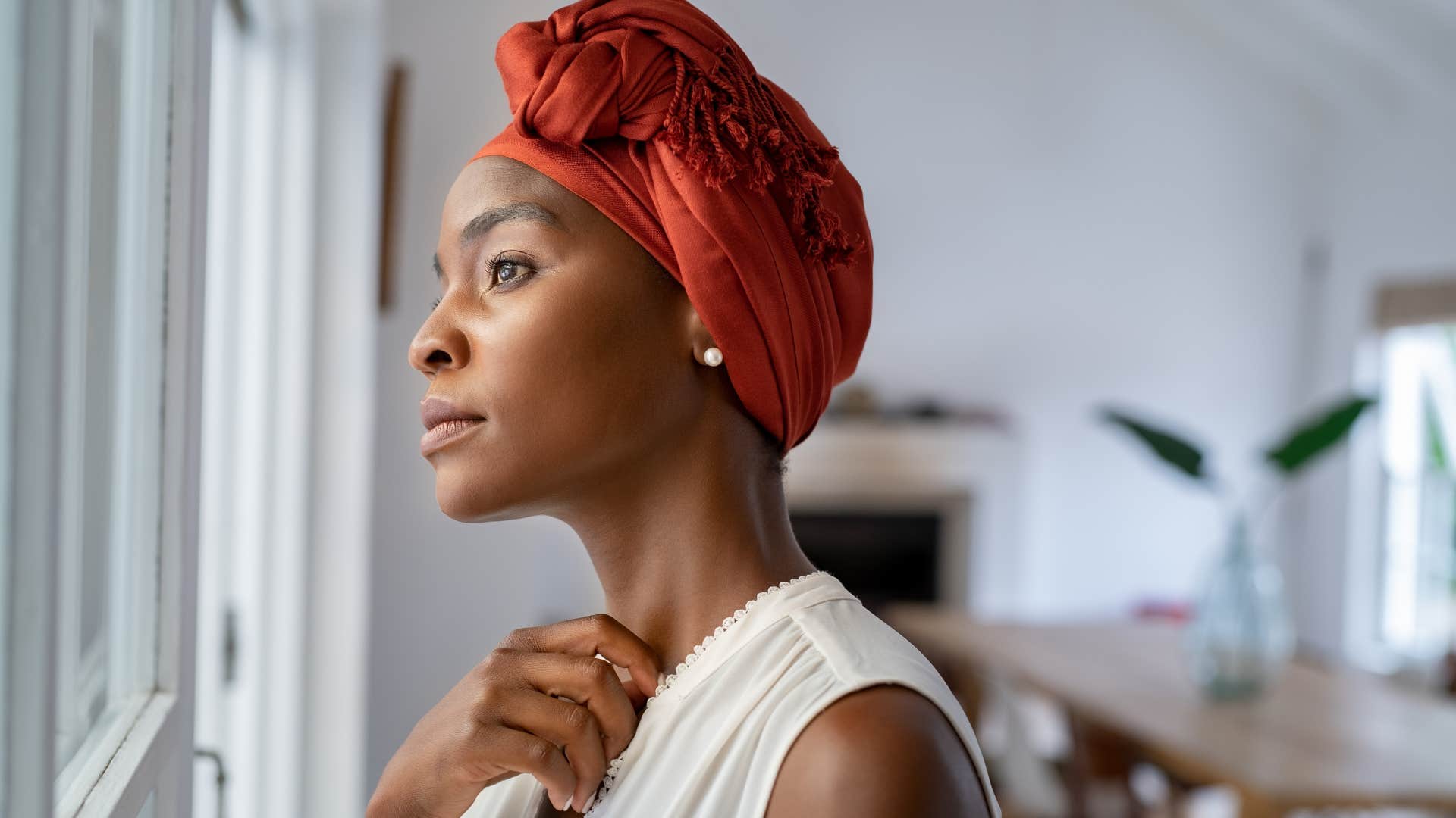 solemn woman looking out a window holding in emotions
