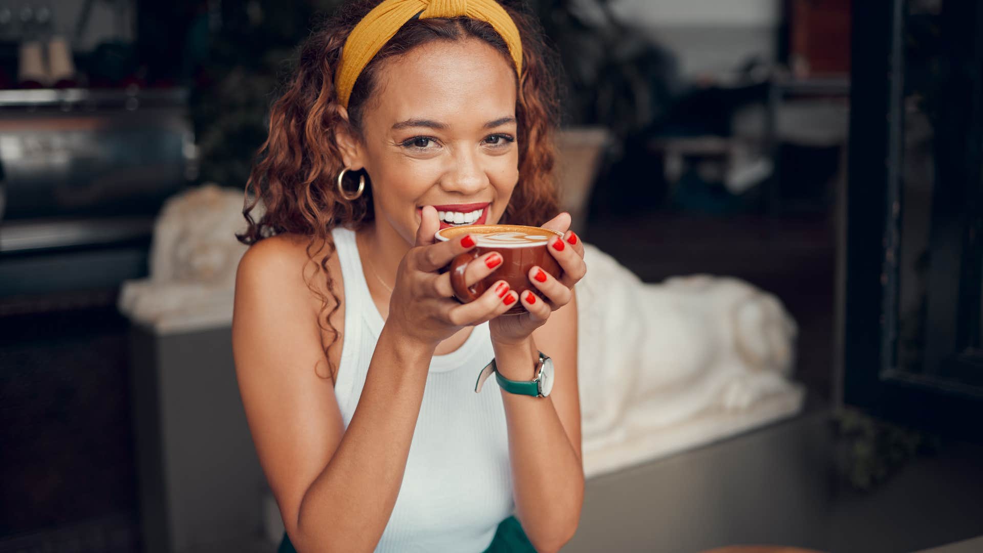 Young woman smiling and drinking cows milk out of a coffee mug