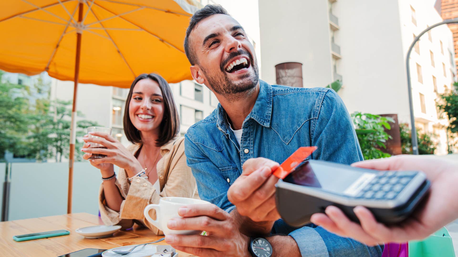 Gen Z man smiling and paying for a coffee with his credit card
