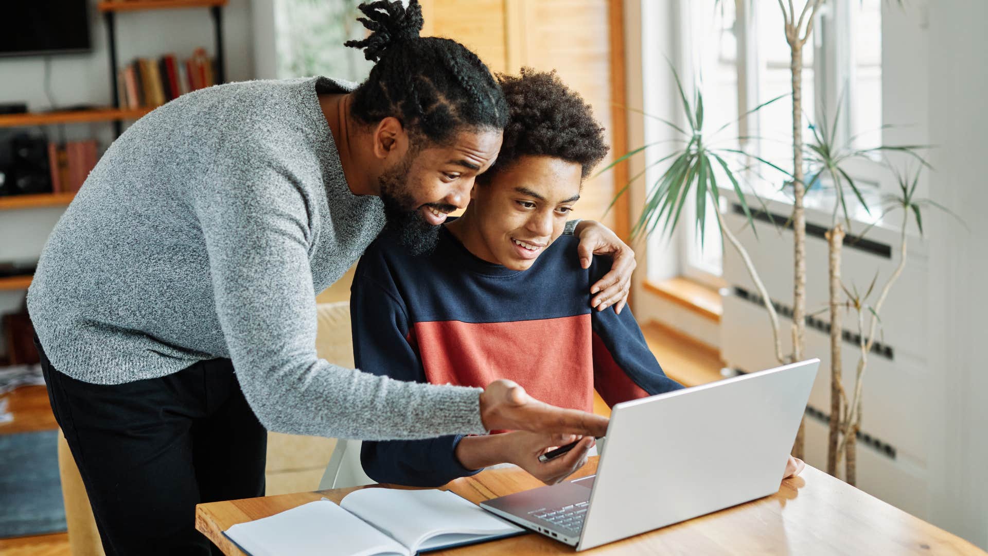 dad hovering over kid working on laptop