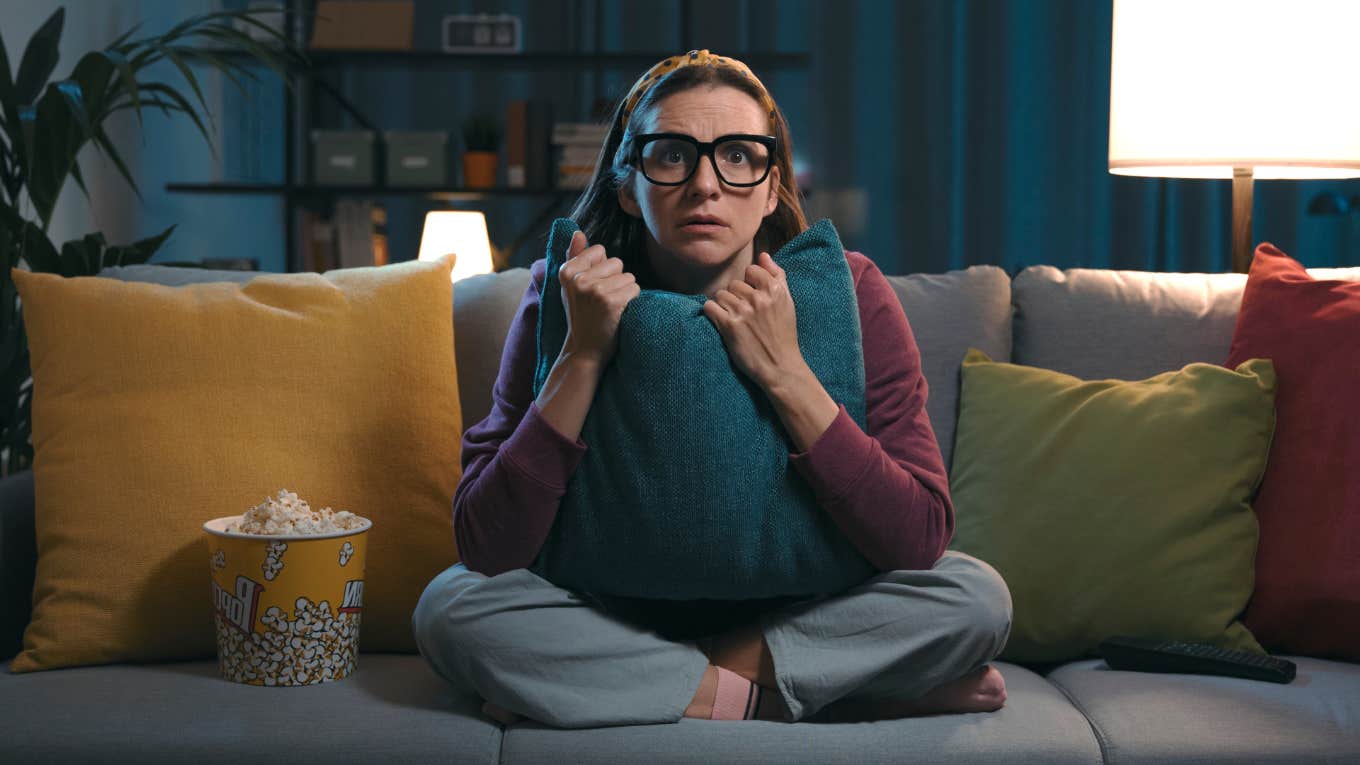 Horror Movie Cliches That Can Actually Happen In Real Life, According To Research scared woman watching movie with popcorn